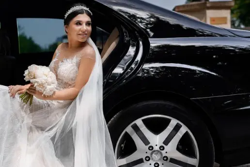 novia vestida de boda blanco largo sentada Mercedes Benz gama alta con conductor puerta abierta